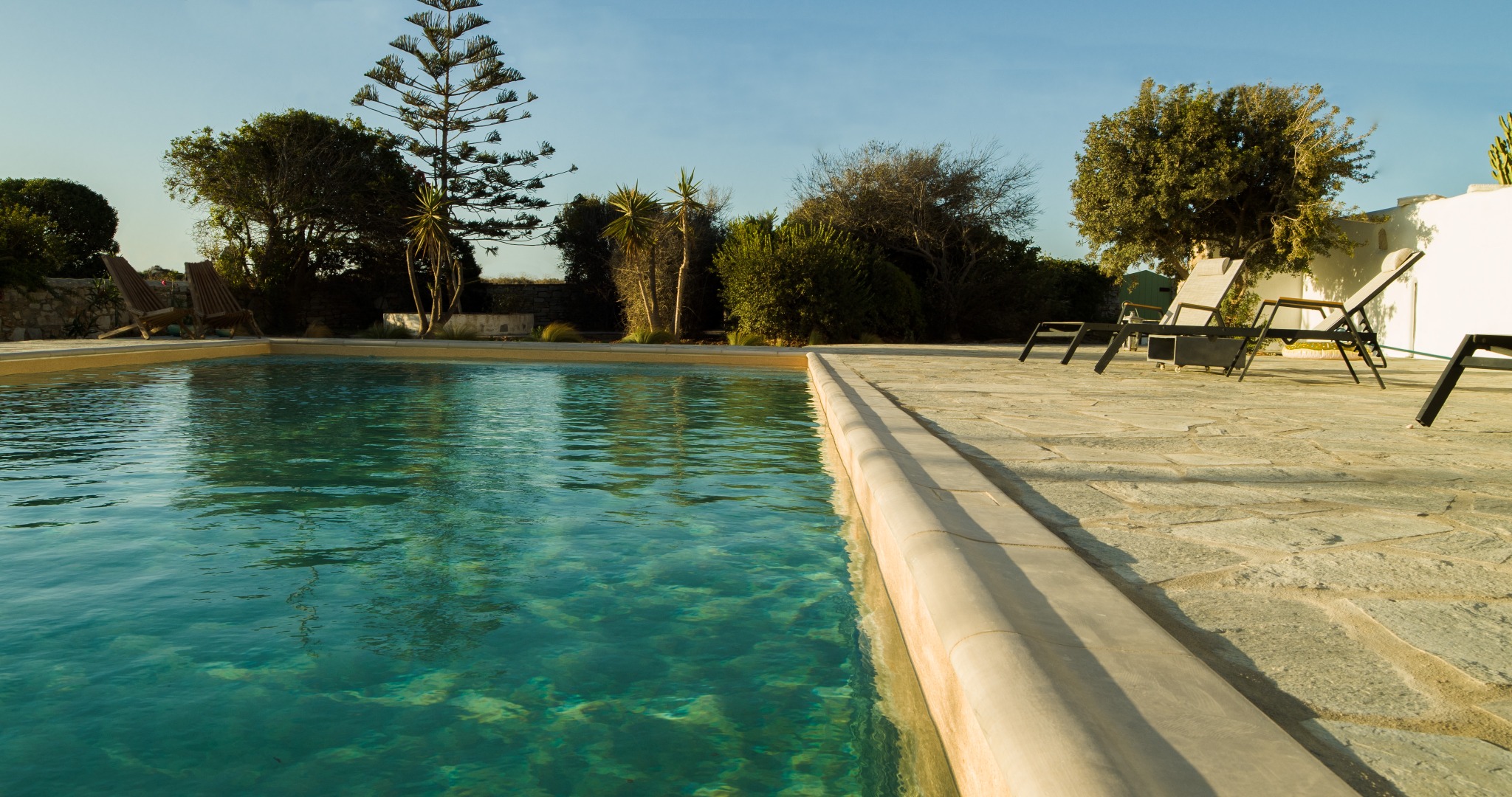Lithos Private Estate clear pool water and sunlit stone deck